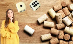 Une jeune femme réfléchit devant des dés et une pile de bouchons. Elle semble hésiter avant de commencer un jeu du bouchon.
