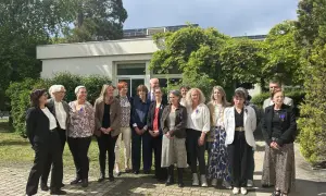 Un groupe de personnes, dont un officier d'académie, pose devant un bâtiment.