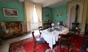 Salle à manger du **château de Saché**, avec une table dressée, un buffet orné et des murs aux motifs décoratifs.