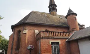 L'église en briques rouges de Saint-Venant, avec son clocher pointu et sa tourelle, semble prête pour un match de basket.