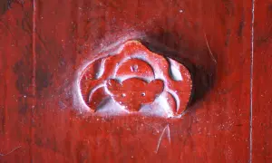 Gravure rouge sur bois, un symbole de chauve-souris, évoquant la chance et la longévité.