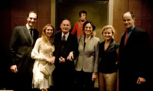 Cinq personnes posent devant un portrait de Napoléon.