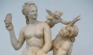 Sculpture grecque antique : Vénus, un putto ailé et un satyre. La déesse tient un objet brisé.