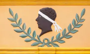 Bas-relief d'une tête d'homme noir, ornée d'un bandeau blanc, entourée de feuilles de laurier. Une évocation des maures origine.