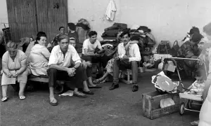 Un groupe de personnes, dont des hommes, des femmes et un bébé, attendent, reflétant le caractère des pieds-noirs dans l'attente.