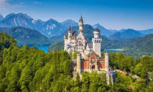 Le château de Neuschwanstein, un joyau parmi le top 10 des plus grands châteaux du monde, se dresse majestueusement sur une colline boisée, dominant un lac bleu et des montagnes imposantes.