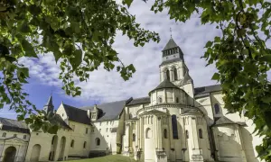 L'abbaye de Fontevraud, vue à travers des feuilles vertes. Combien de temps pour visiter Fontevraud ? Prévoyez une journée entière pour explorer ce site historique.