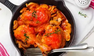 Poulet Marengo mijoté dans une poêle en fonte avec des champignons et garni de thym.