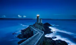 Un phare solitaire, tel un gardien des mers, éclaire la nuit. Son faisceau puissant guide les navires, rappelant les vers de Baudelaire sur la beauté sombre de l'océan.