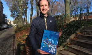 Un homme tient un livre intitulé "Dans l'histoire du Camp des Loges", avec des images de football sur la couverture.