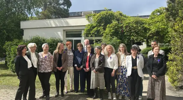 Un groupe de personnes, dont un officier d'académie, pose devant un bâtiment.