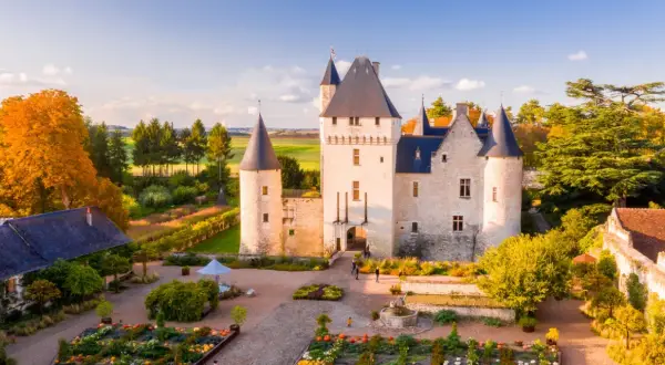 Le château du Rivau, propriété de la famille, s'illumine sous le soleil d'automne, entouré de jardins colorés.