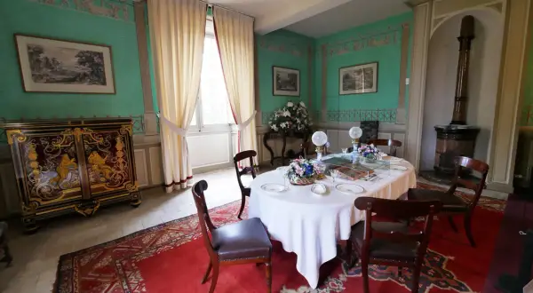 Salle à manger du **château de Saché**, avec une table dressée, un buffet orné et des murs aux motifs décoratifs.