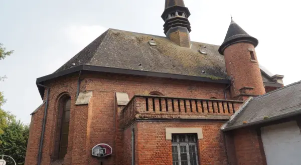 L'église en briques rouges de Saint-Venant, avec son clocher pointu et sa tourelle, semble prête pour un match de basket.