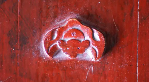 Gravure rouge sur bois, un symbole de chauve-souris, évoquant la chance et la longévité.