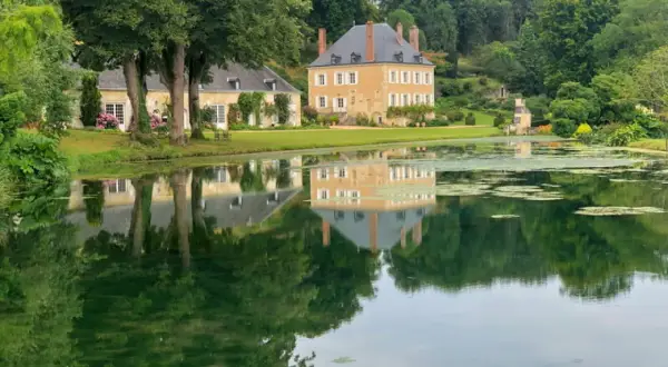 Le jardin du Plessis Sasnières, avec son étang paisible reflétant le château et ses arbres majestueux, offre une vue d'une beauté intemporelle.