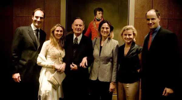 Cinq personnes posent devant un portrait de Napoléon.