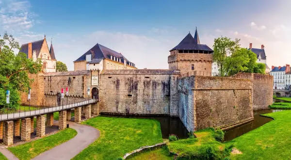 Le majestueux **Château de Nantes** se dresse fièrement, entouré de douves verdoyantes et d'une pelouse impeccable. Un pont mène à son entrée fortifiée.