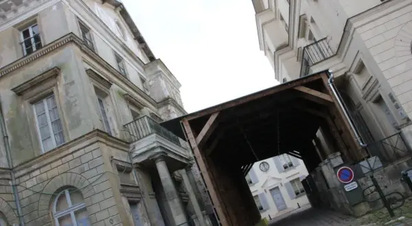 Passage couvert menant au palais du roi de Rome, avec des bâtiments anciens et une cour pavée.