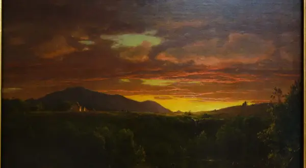Un paysage de crépuscule, baigné de lumières orangées et dorées, évoquant la beauté mélancolique d'un crépuscule victor hugo. Des montagnes se dressent à l'horizon, tandis que des lumières douces émanent de quelques habitations.