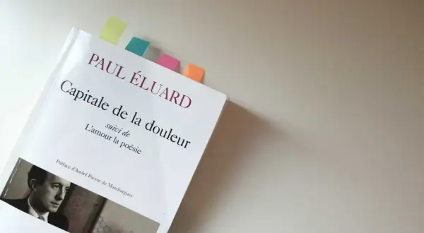 Un livre ouvert, "Capitale de la douleur" de Paul Éluard, marqué par des post-its colorés.