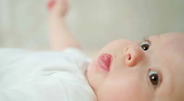 Un bébé aux yeux curieux sort sa langue, un geste innocent dont la signification peut varier.