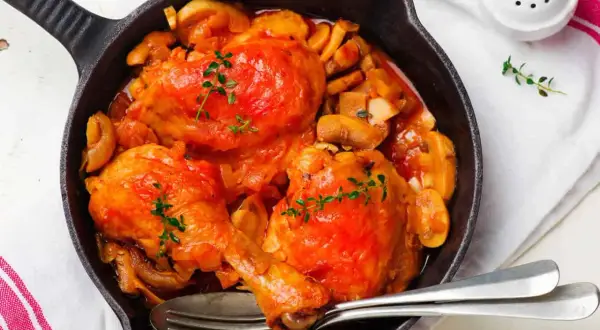 Poulet Marengo mijoté dans une poêle en fonte avec des champignons et garni de thym.