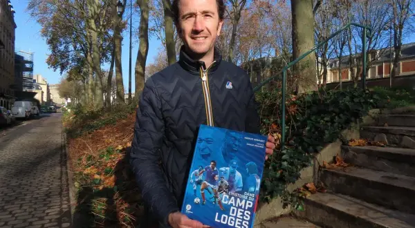 Un homme tient un livre intitulé "Dans l'histoire du Camp des Loges", avec des images de football sur la couverture.