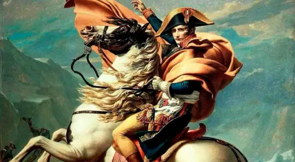 Napoléon, sur son cheval blanc, lève un bras vers le ciel. Sa cape orange flotte au vent, accentuant la taille de Napoléon.