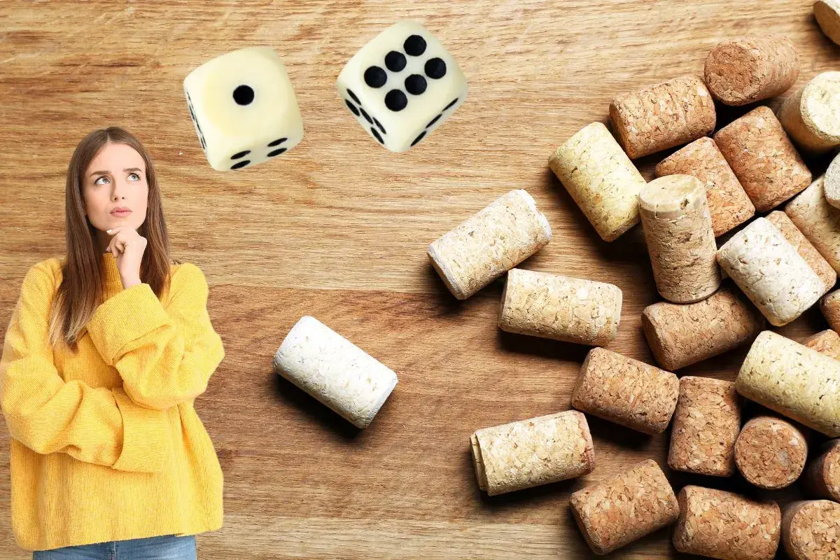 Une jeune femme réfléchit devant des dés et une pile de bouchons. Elle semble hésiter avant de commencer un jeu du bouchon.