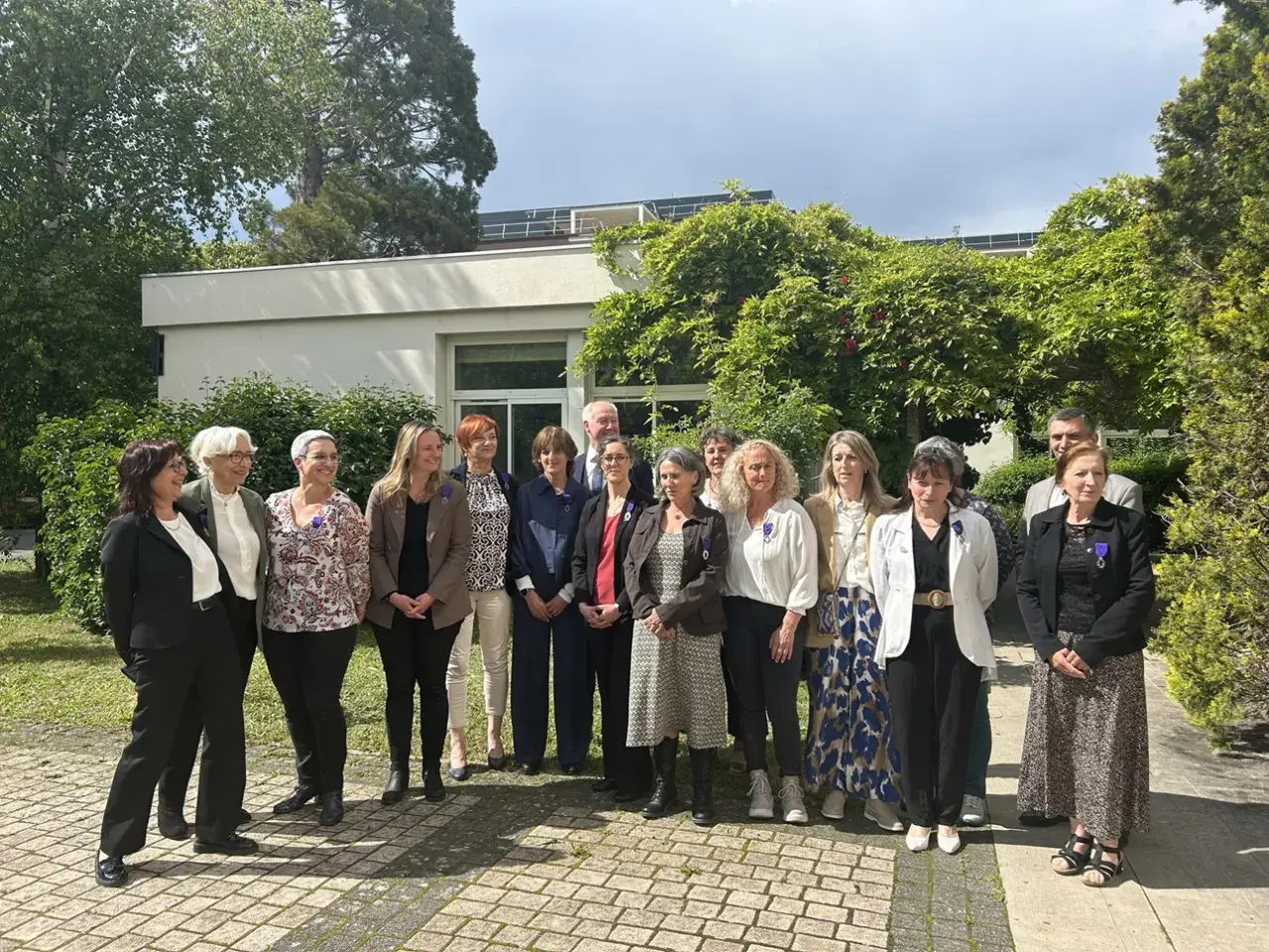 Un groupe de personnes, dont un officier d'académie, pose devant un bâtiment.