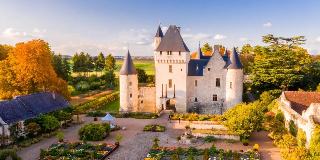 Le château du Rivau, propriété de la famille, s'illumine sous le soleil d'automne, entouré de jardins colorés.
