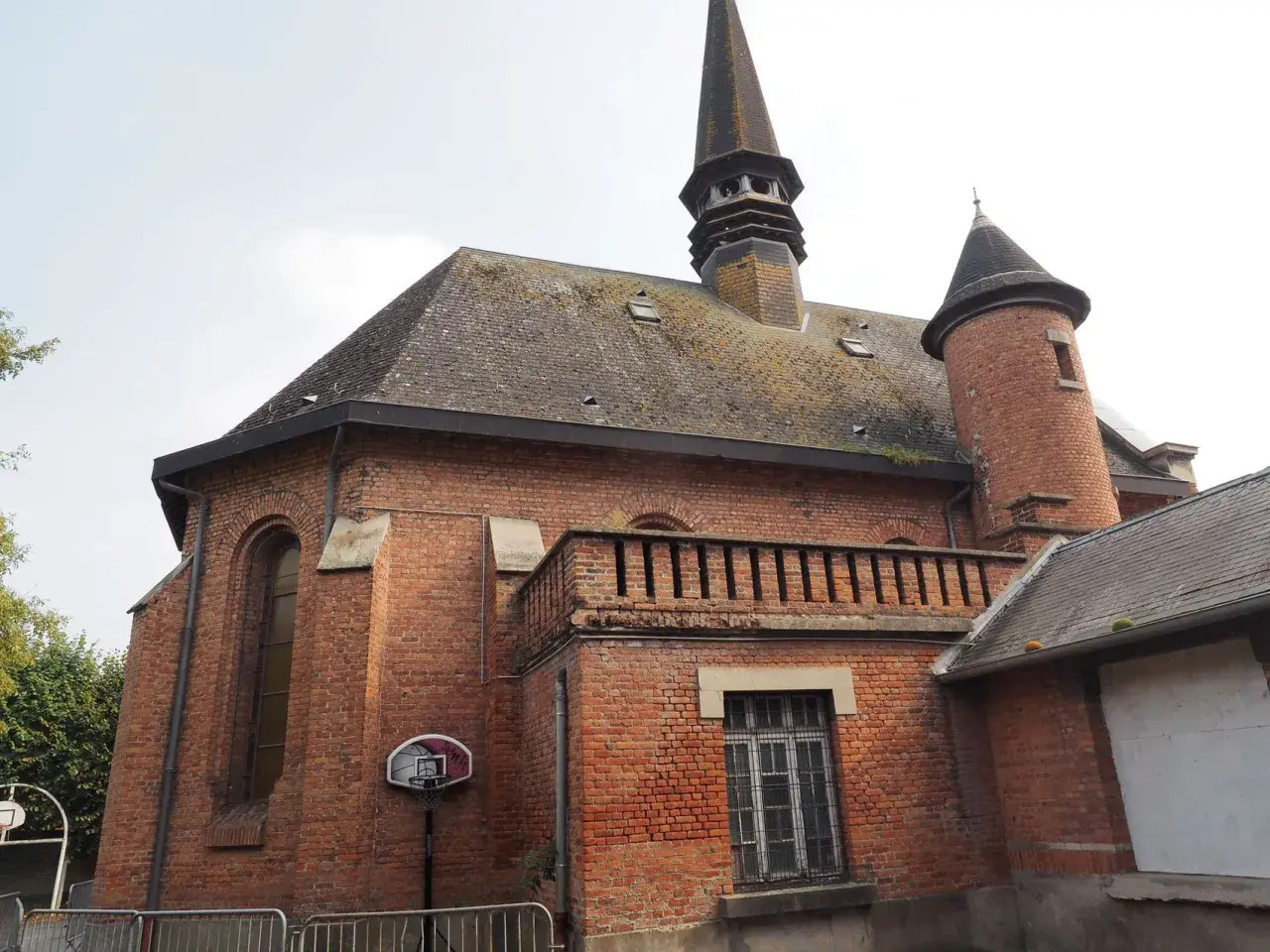 L'église en briques rouges de Saint-Venant, avec son clocher pointu et sa tourelle, semble prête pour un match de basket.