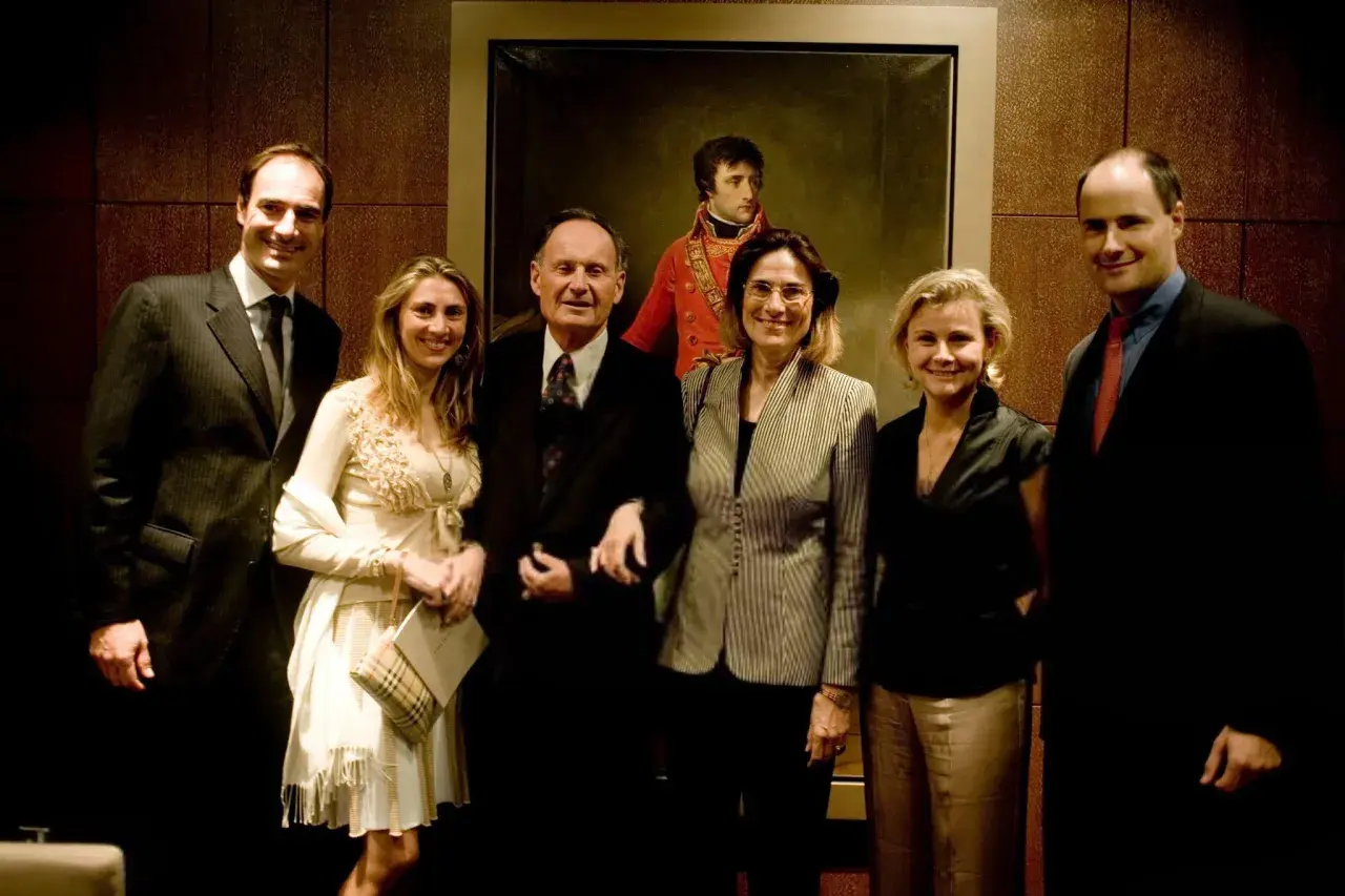Cinq personnes posent devant un portrait de Napoléon.