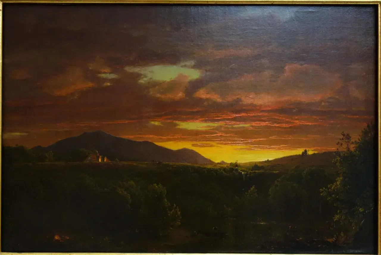 Un paysage de crépuscule, baigné de lumières orangées et dorées, évoquant la beauté mélancolique d'un crépuscule victor hugo. Des montagnes se dressent à l'horizon, tandis que des lumières douces émanent de quelques habitations.