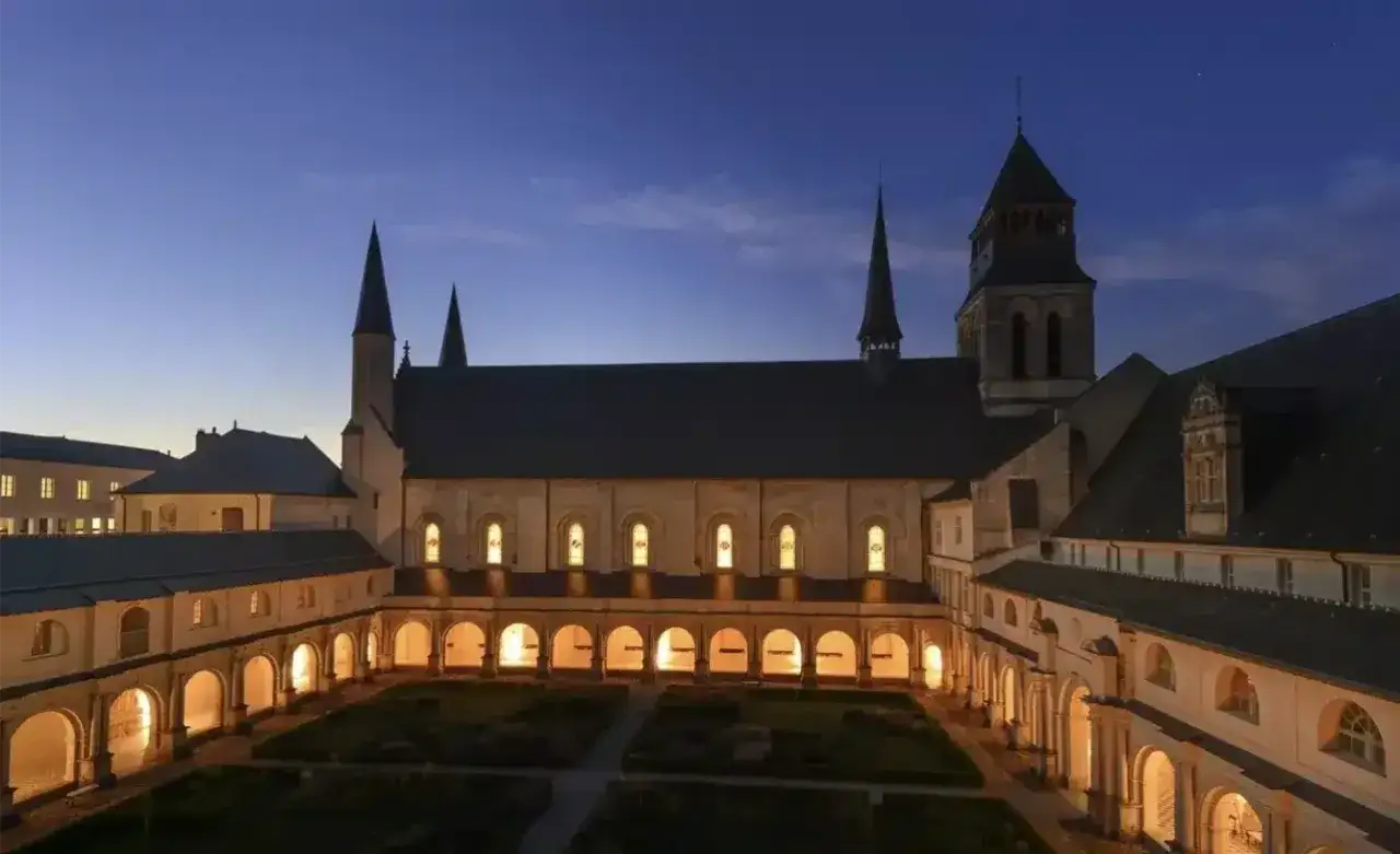 Abbaye de Fontevraud illumin&eacute;e la nuit. Pour savoir combien de temps pour visiter Fontevraud, pr&eacute;voyez une journ&eacute;e enti&egrave;re pour explorer ce lieu historique.