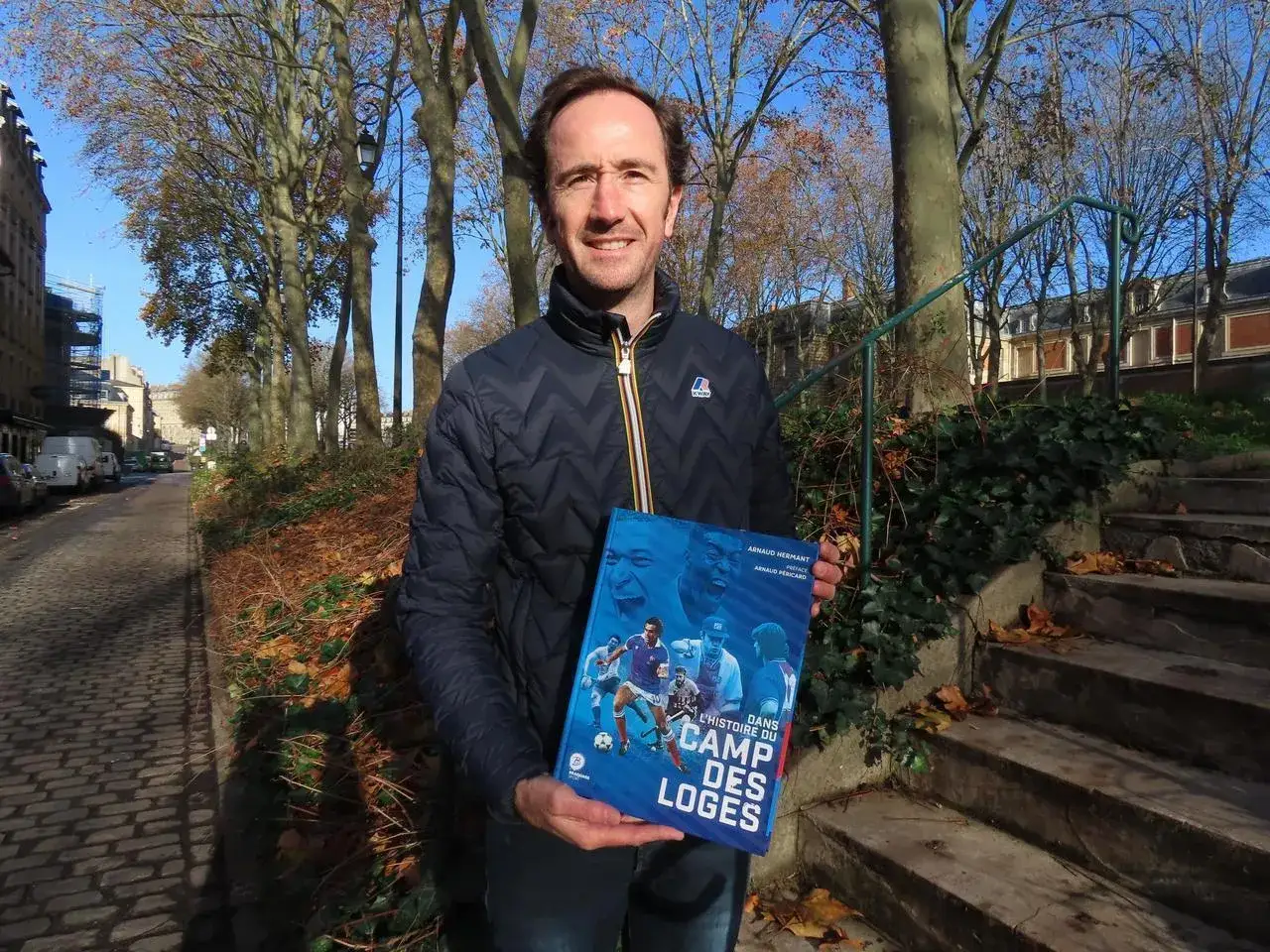 Un homme souriant tient un livre intitul&eacute; 