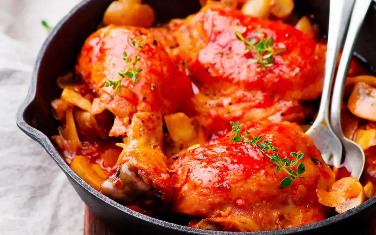 Un savoureux poulet Marengo mijot&eacute; dans une sauce tomate riche, garni de thym frais, servi dans une po&ecirc;le en fonte avec des champignons.