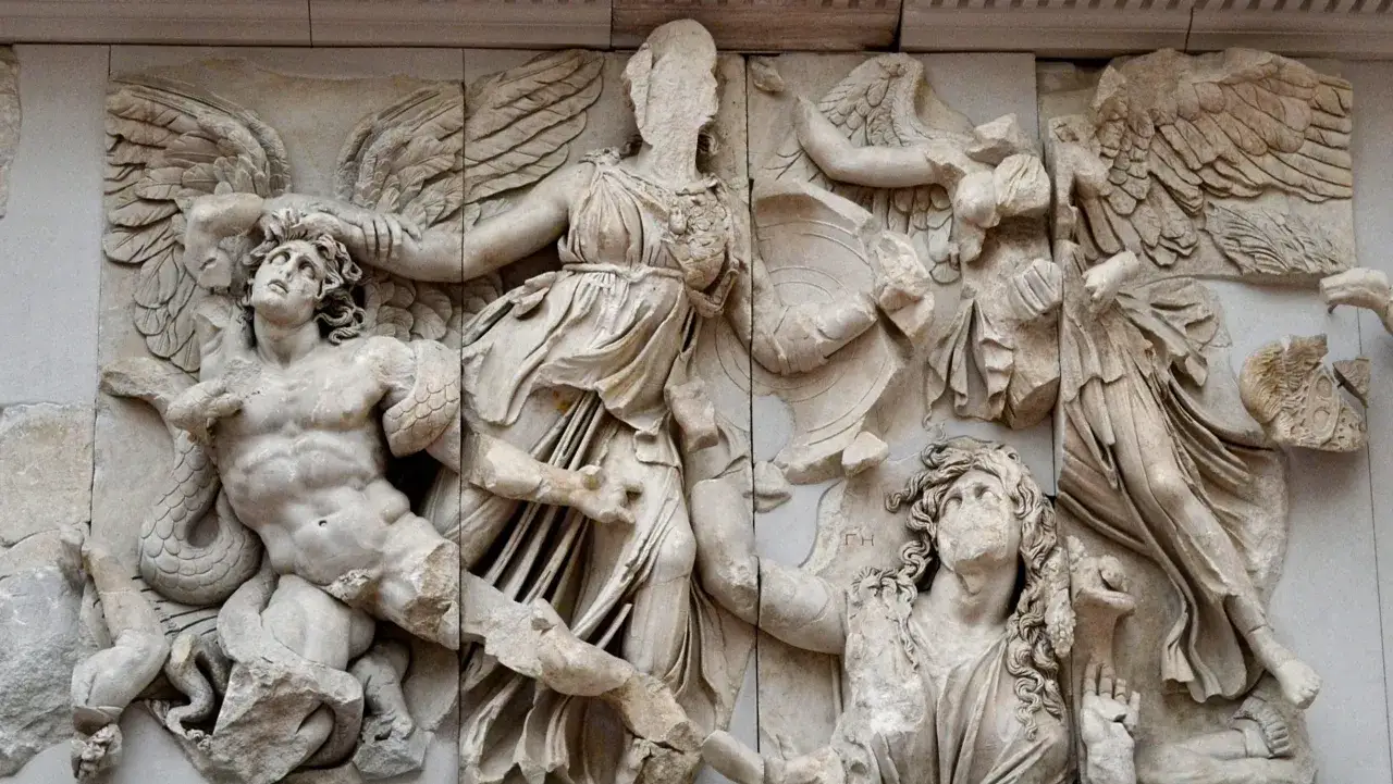 Relief sculpté du grand autel de Pergame, représentant des figures mythologiques en lutte, avec des ailes et des serpents.