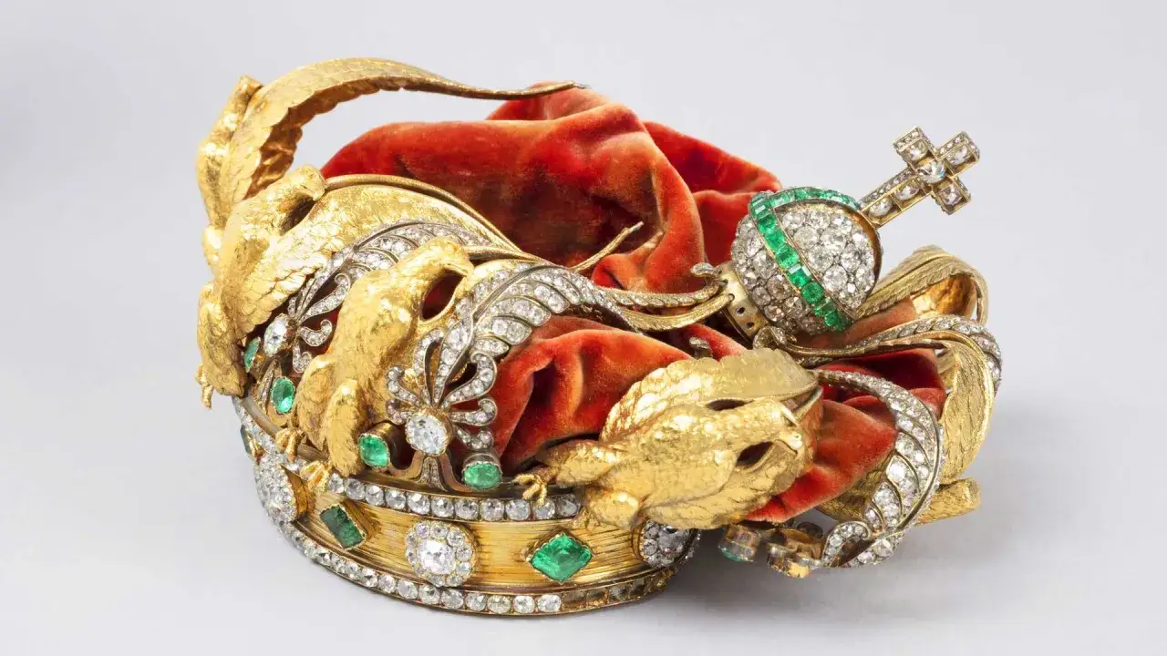 Magnifique couronne de l'imp&eacute;ratrice Eug&eacute;nie, orn&eacute;e d'aigles dor&eacute;s, de diamants et d'&eacute;meraudes, pos&eacute;e sur un velours rouge.
