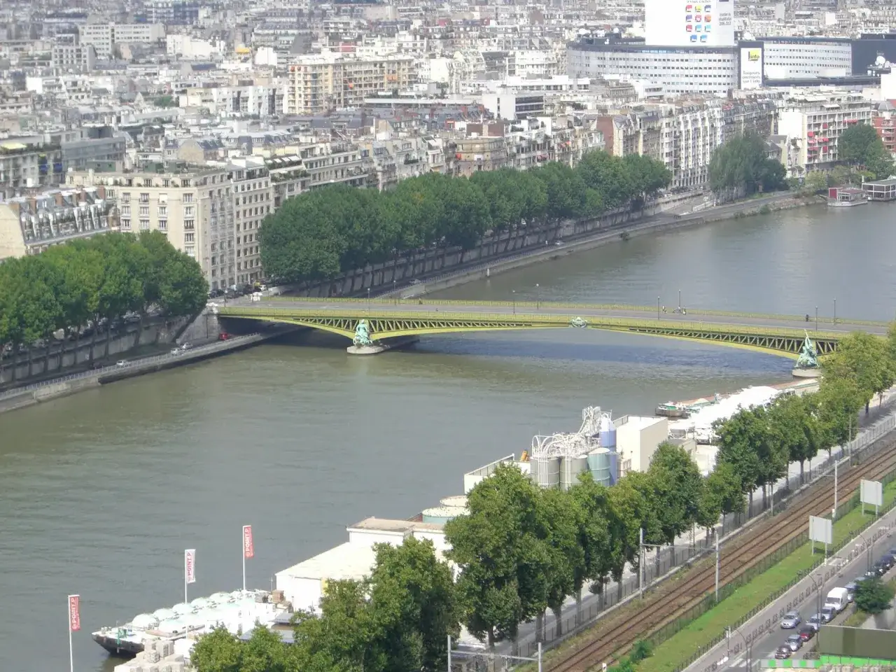Vue a&eacute;rienne de Paris, le pont Mirabeau jaune enjambe la Seine, entour&eacute; de b&acirc;timents et d'arbres. Une analyse visuelle de ce pont embl&eacute;matique.