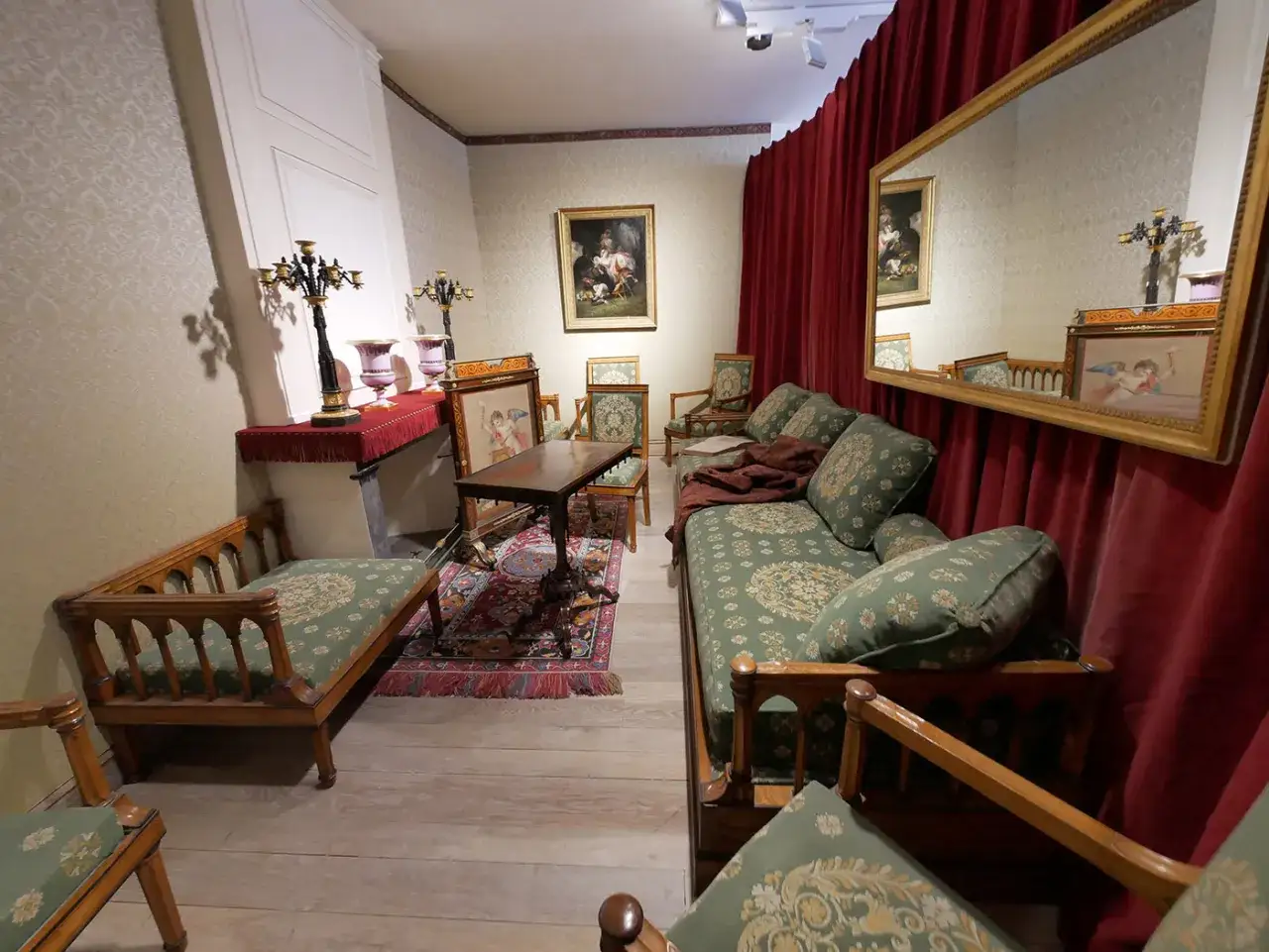 Salon du chateau de Sach&eacute;, avec canap&eacute;s fleuris, tapis persan et grand miroir refl&eacute;tant une pi&egrave;ce &eacute;l&eacute;gante.