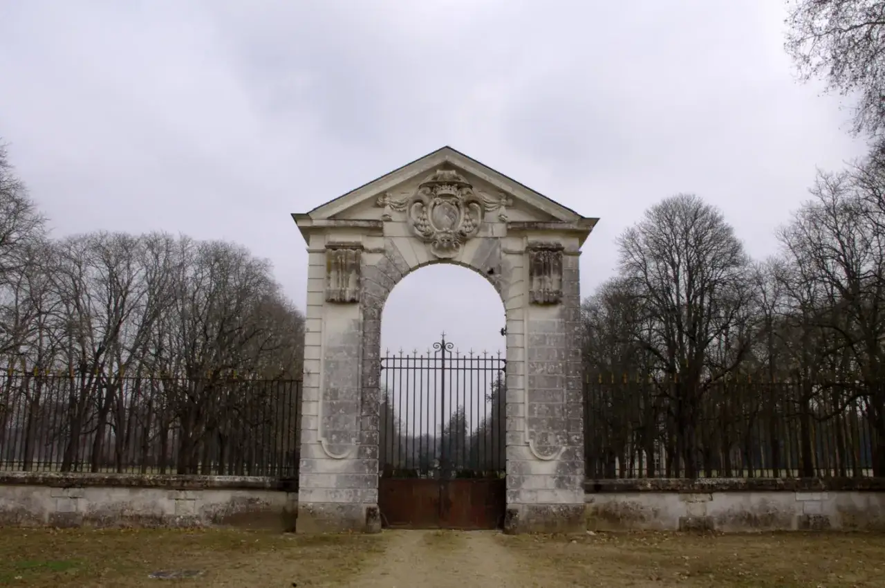 Portail monumental menant au ch&acirc;teau de Richelieu, orn&eacute; d'un blason. Arbres d&eacute;nud&eacute;s et ciel gris.
