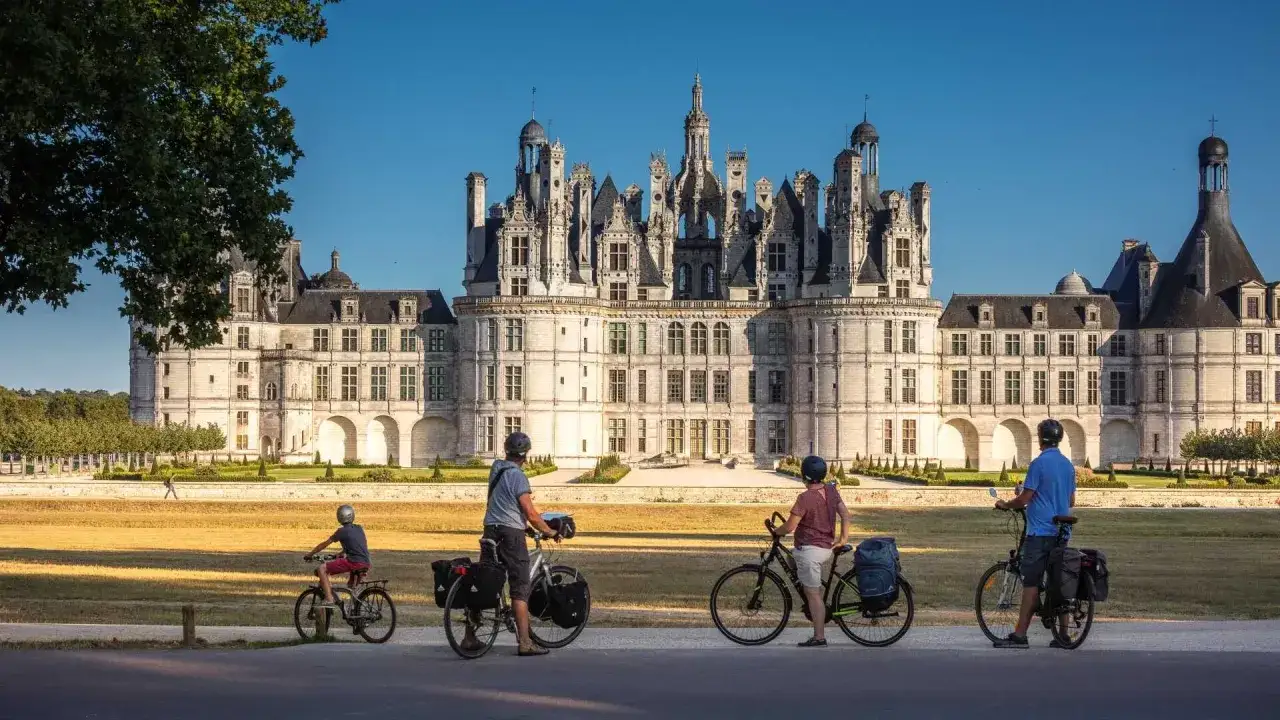 Famille &agrave; v&eacute;lo devant le majestueux Ch&acirc;teau de Chambord, un joyau de la Loire.
