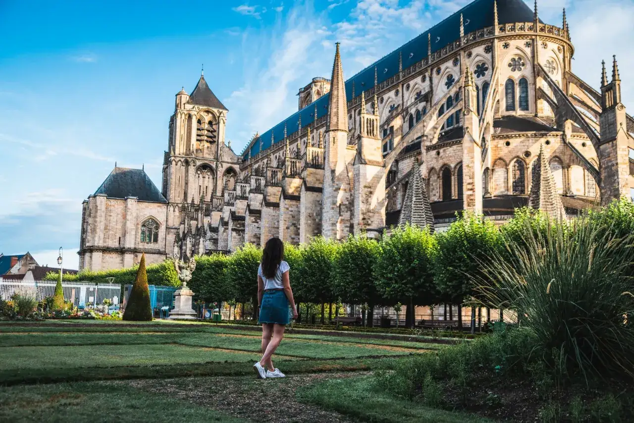 Une femme admire la majestueuse cath&eacute;drale de Bourges, un chef-d'&oelig;uvre gothique, rappelant l'opulence du ch&acirc;teau Jacques C&oelig;ur voisin.