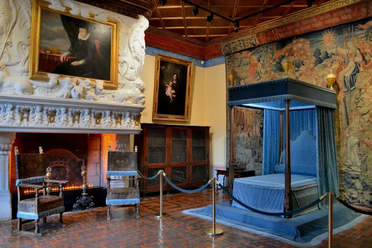 Int&eacute;rieur du ch&acirc;teau de Chenonceau : chemin&eacute;e monumentale, portraits, lit &agrave; baldaquin bleu et tapisseries d'&eacute;poque.