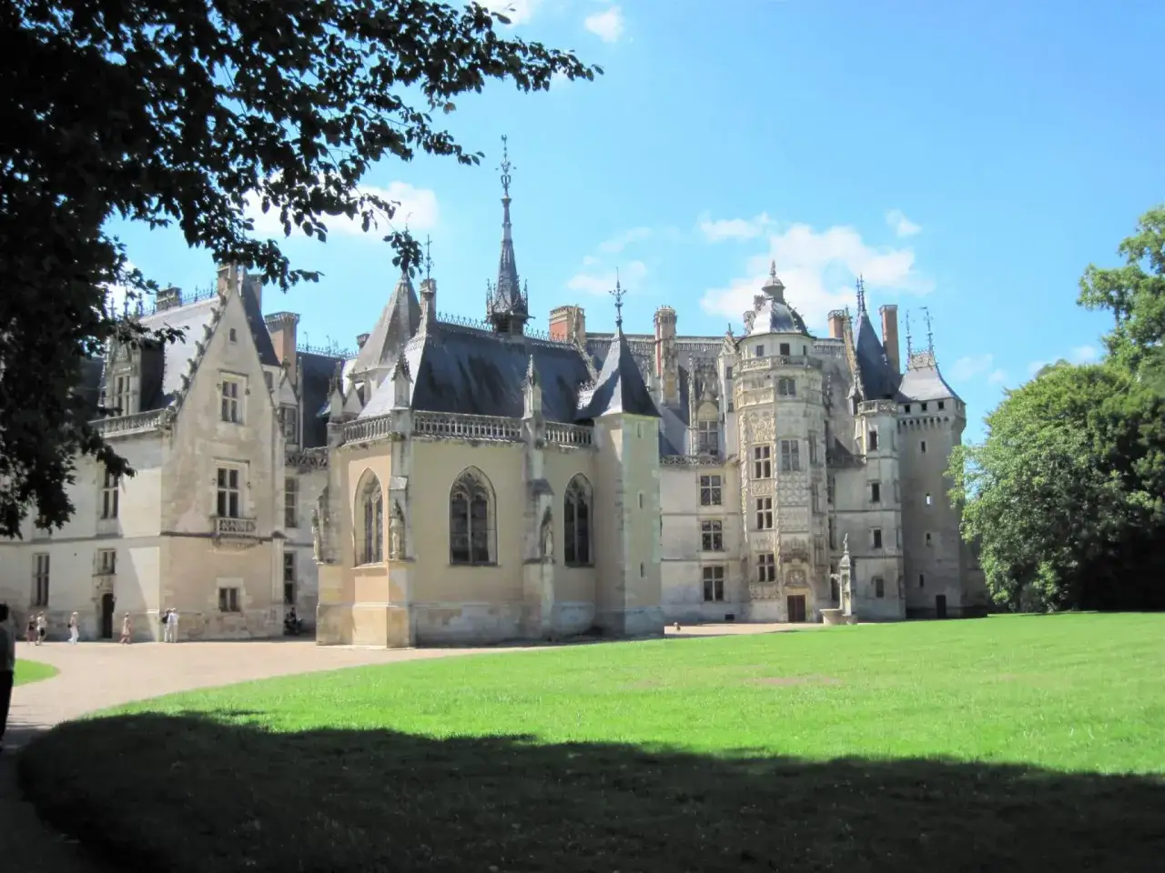 Magnifique ch&acirc;teau dans le Cher, avec ses tours &eacute;lanc&eacute;es et son parc verdoyant sous un ciel bleu.