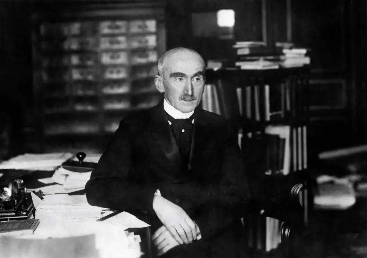 Henri Bergson, pensif, réfléchit au temps dans son bureau, entouré de livres.