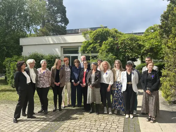 Un groupe de personnes, dont un officier d'académie, pose devant un bâtiment.