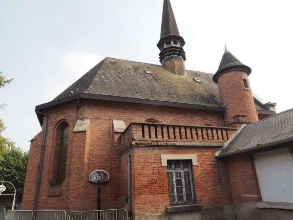 L'église en briques rouges de Saint-Venant, avec son clocher pointu et sa tourelle, semble prête pour un match de basket.